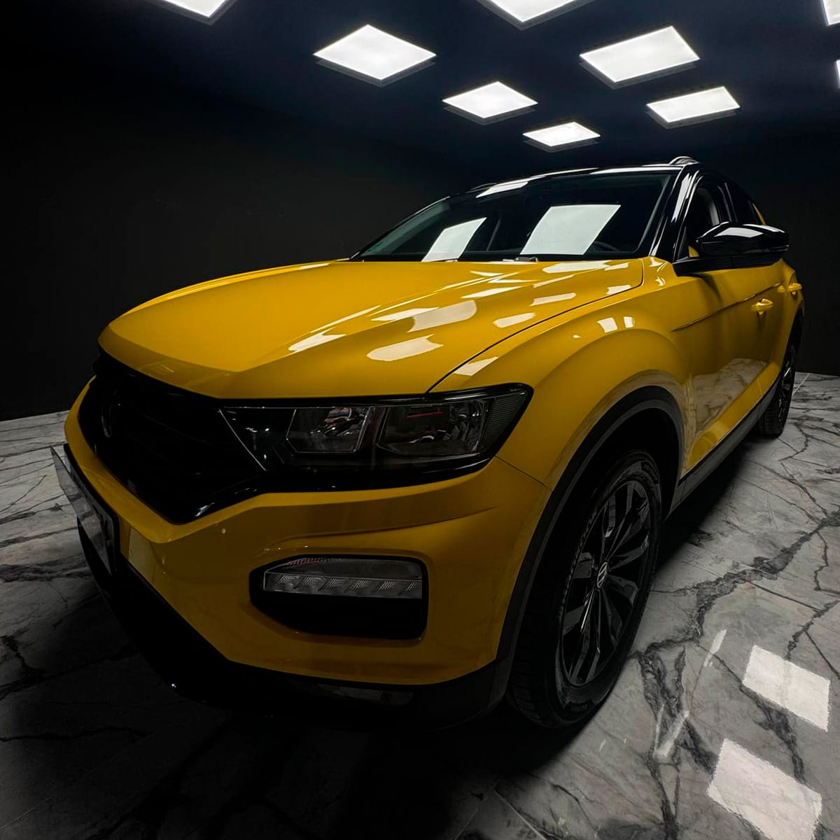 Volkswagen T-Roc amarillo con alto brillo bajo focos; aplicación de recubrimiento cerámico en CDW Llacer.