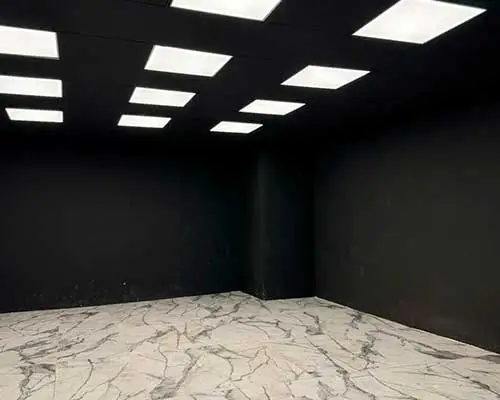 Sala de detailing con paredes oscuras e iluminación de techo para inspección de pintura y acabados